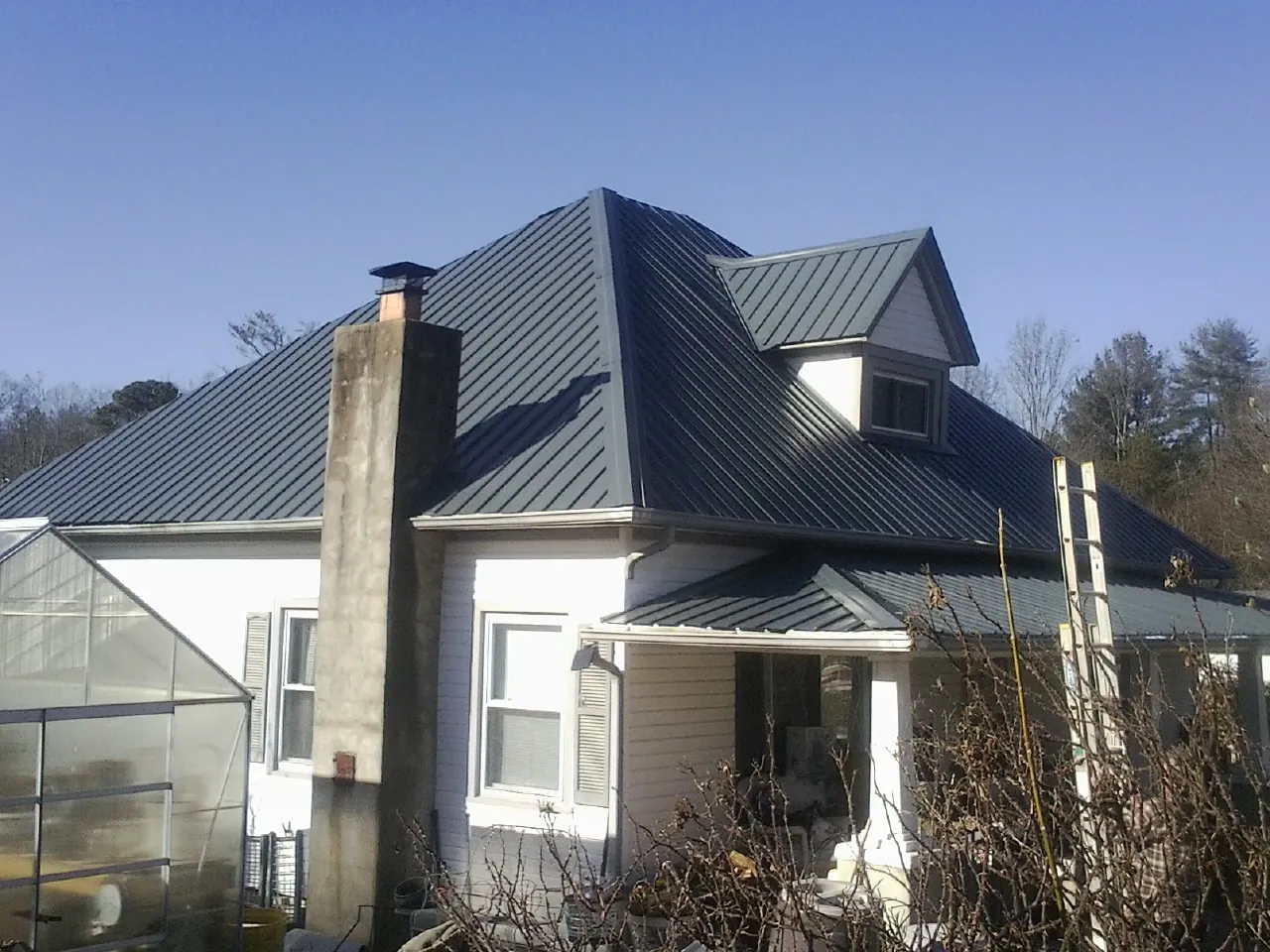 Dark blue standing seam metal roof on a white farmhouse with dormer — Slate & Tile Roof Repair by Roofing Brothers in Great Cacapon