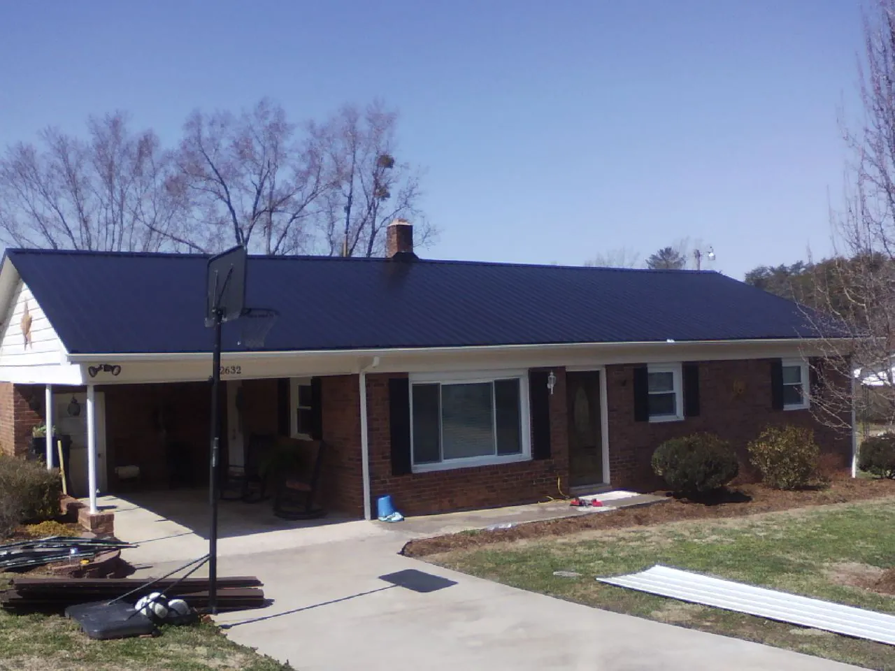 Finished dark blue metal roof on a brick ranch with a carport in Great Cacapon