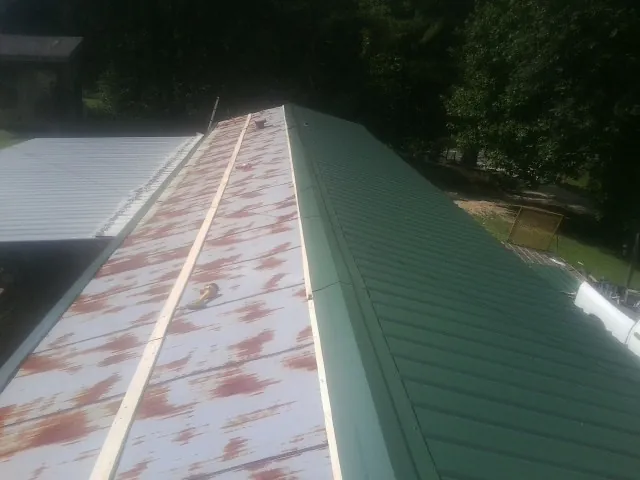 Old rusted panels beside newly installed green metal roofing — Wind Damage Roof Repair by Roofing Brothers in Great Cacapon