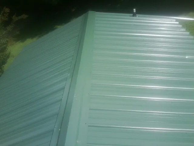 New green metal panels meeting at the ridge of a roof — Flat Roof Repair work by our crew in Great Cacapon