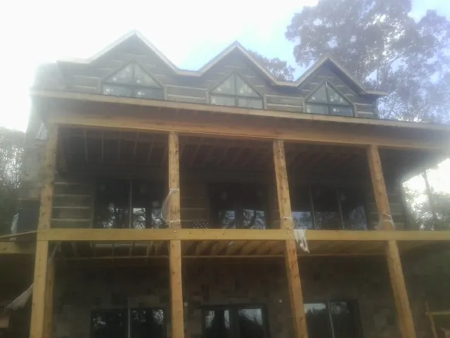 Dormers and porch framing on a large log home under construction — Roof Coating work by our crew in Great Cacapon