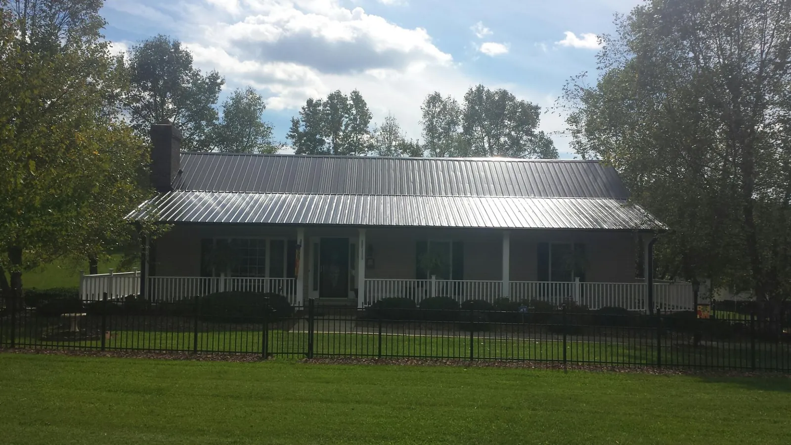 Gray metal roof on a brick ranch with a full width front porch — Gutter Guard Installation work by our crew in Great Cacapon