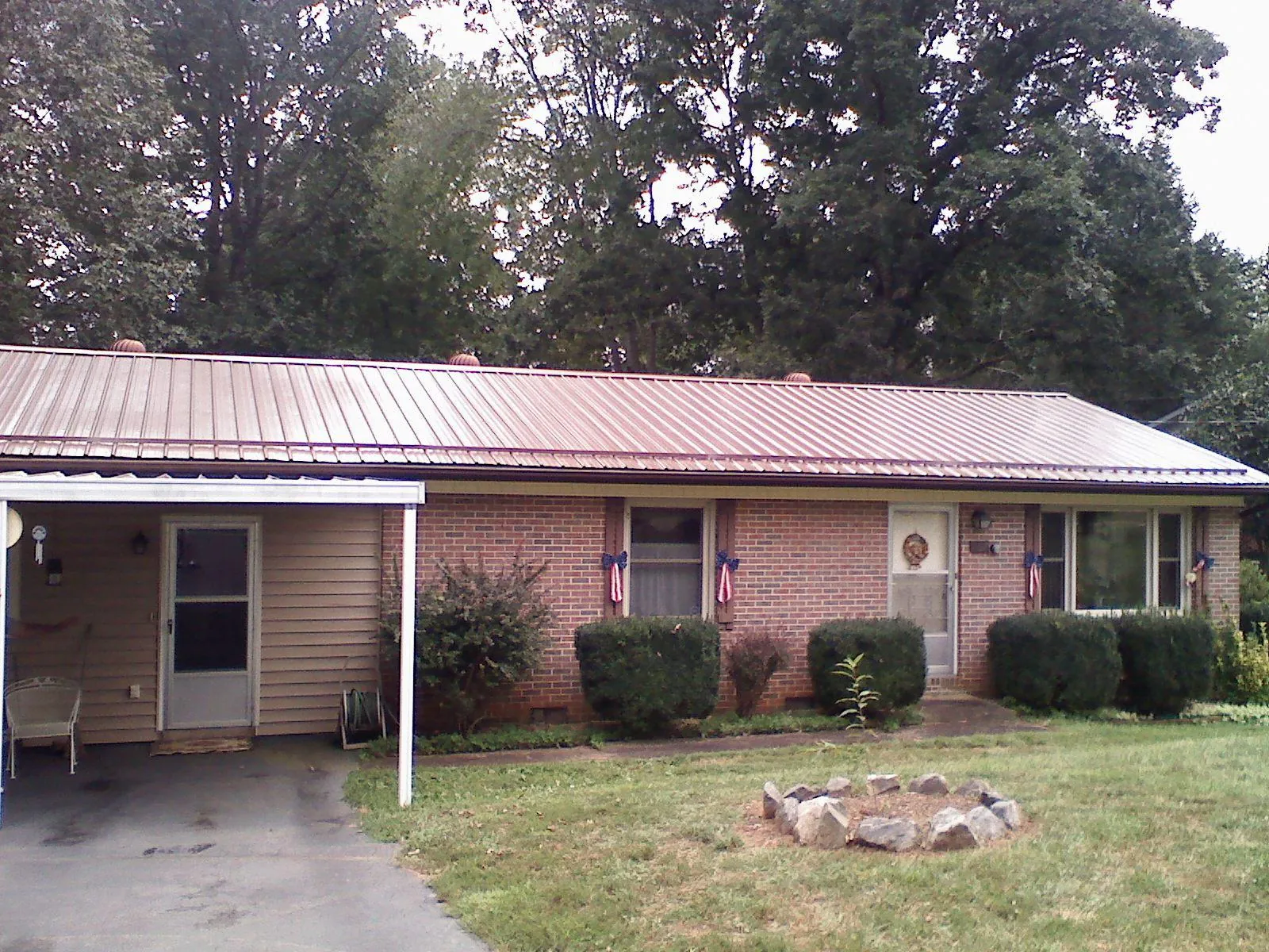 Bronze metal roof and carport on a brick ranch home — Roof Repair work by our crew in Great Cacapon