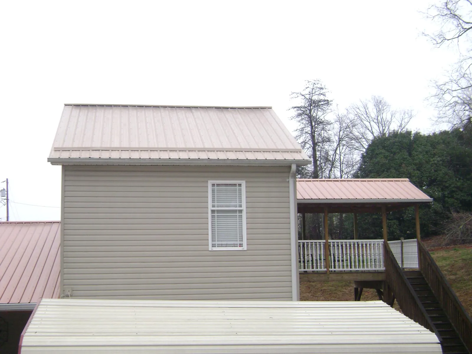 Tan metal roofs on a two story addition and attached porch, from a Roof Replacement job in Great Cacapon