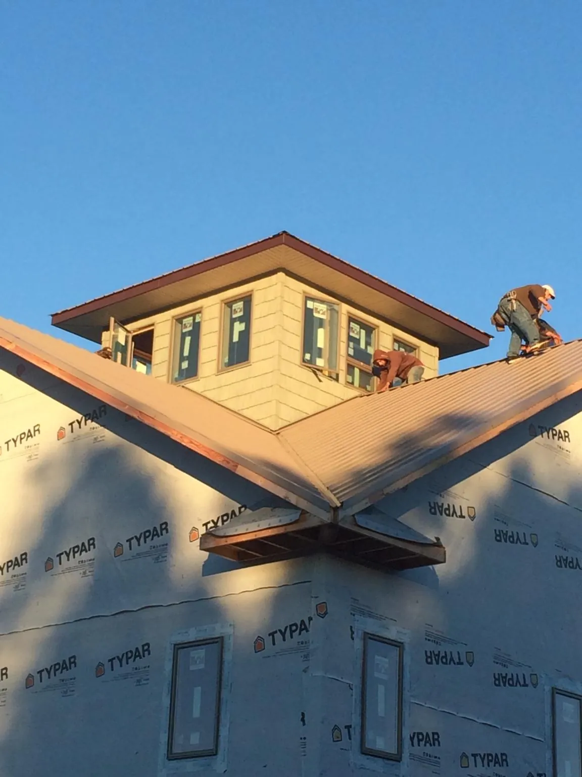 Roofers working around a rooftop cupola on a new metal roof at sunset — Roof Waterproofing in Great Cacapon by Roofing Brothers